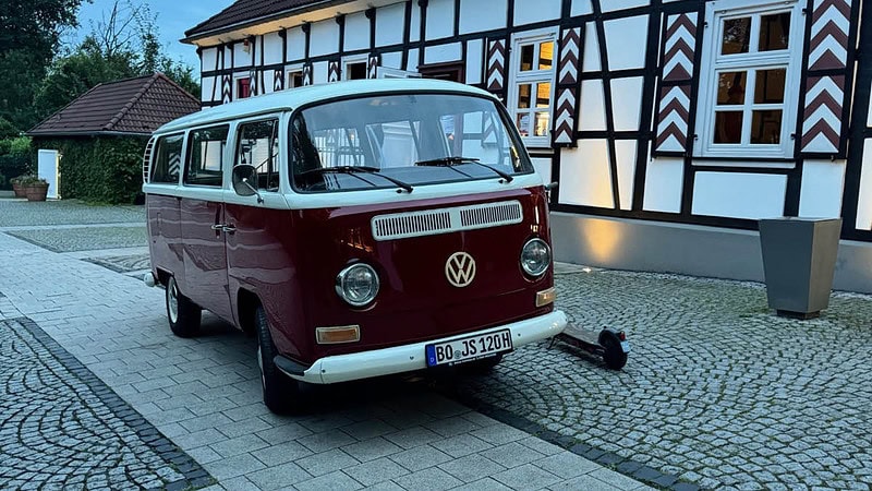 Roter VW Bulli vor einem alten Haus
