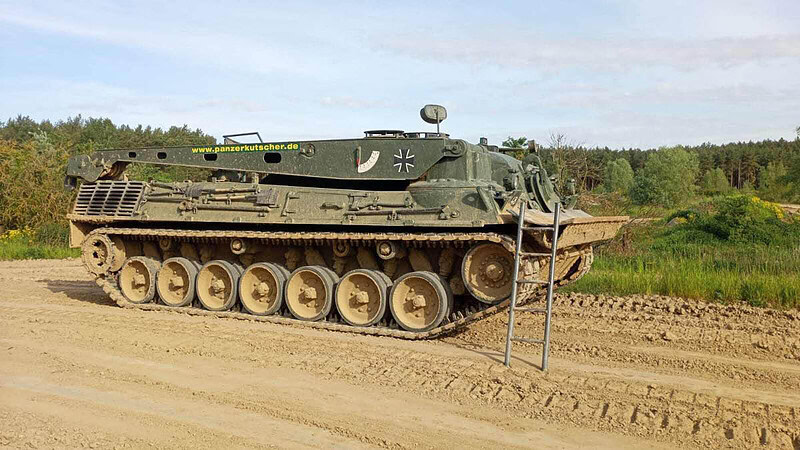 Panzer steht auf Weg, eine Leiter zum hochklettern ist angelehnt.