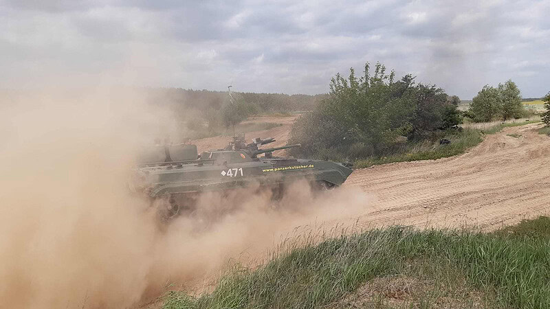 Panzer der durch Dreck fährt und Staub aufwirbelt