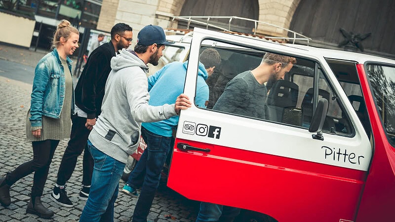 Eine Gruppe steigt in einen VW Bulli ein.