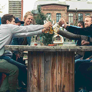 Eine Gruppe stößt an einem Esstisch im freien an.