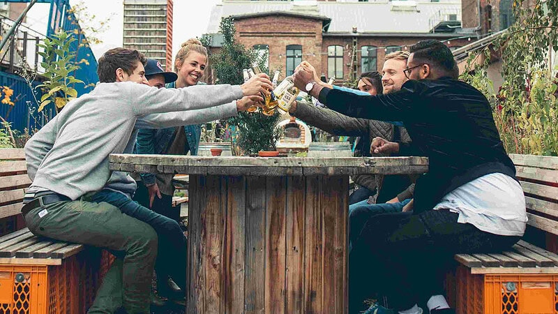 Eine Gruppe stößt an einem Esstisch im freien an.