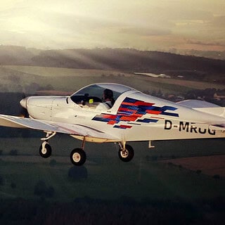 Ein Flugzeug fliegt beim Sonnenuntergang über die Felder.