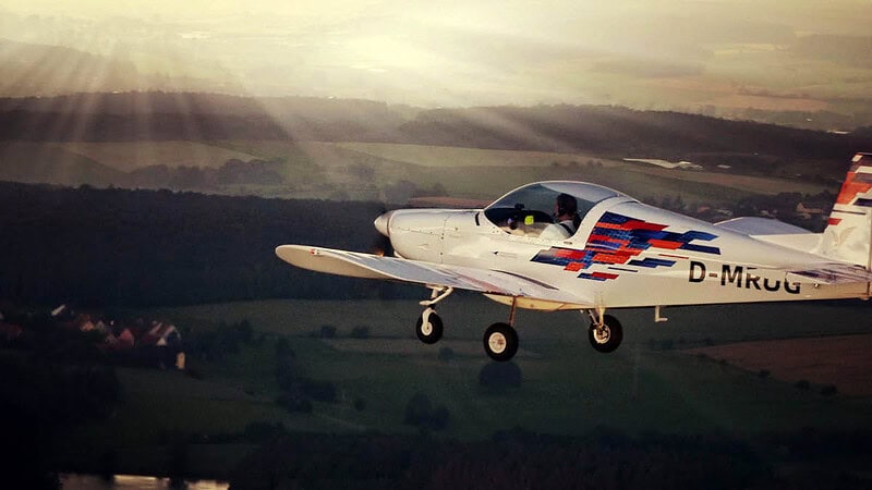 Ein Flugzeug fliegt beim Sonnenuntergang über die Felder.