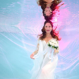 Frau im Hochzeitskleid mit Blumenstrauß unter Wasser Foto