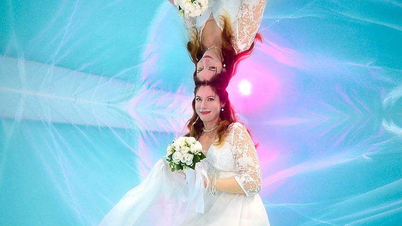 Frau im Hochzeitskleid mit Blumenstrauß unter Wasser Foto seitlich