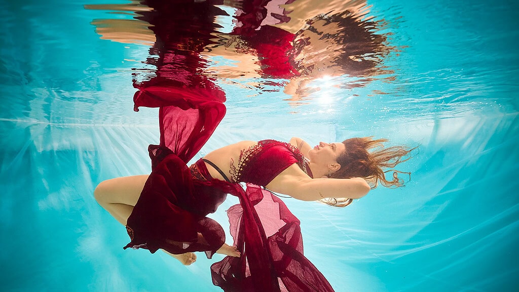 unterwasser-fotoshooting-rotes-kleid Eine Frau posiert schwebend beim Unterwasser Fotoshooting.