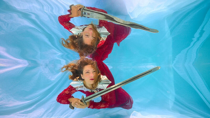 Eine Frau posiert mit einem Schwert beim Unterwasser Fotoshooting.