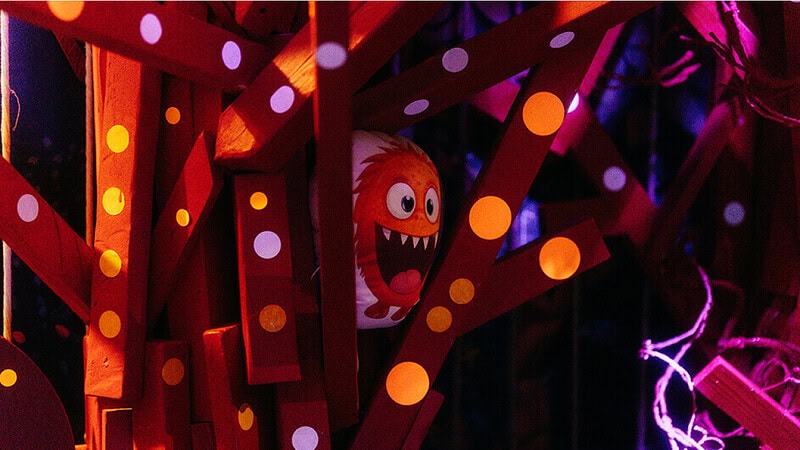 Ein Monster Kissen zwischen Balken was Freundlicht schaut und seine Zähne zeigt