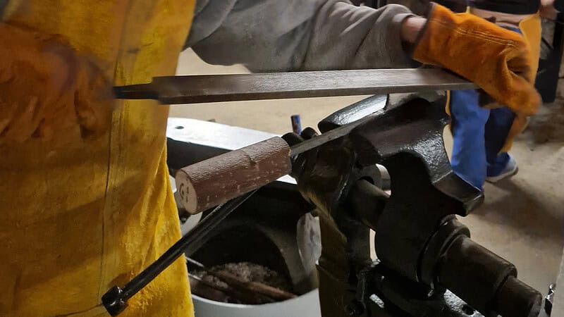 Letzte Handgriffe mit der Handfeile werden erledigt. Das fast fertige Messer ist im Spannstock und wird final bearbeitet.