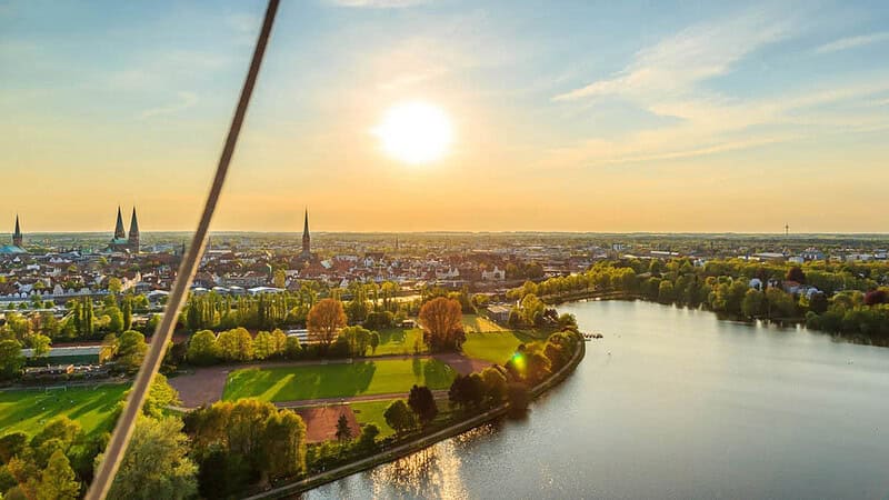 : Aussicht auf Lübeck mit Grünfläche, Innenstadt und Seeabschnitt- Ballonfahrt- Aussicht über Lübeck
