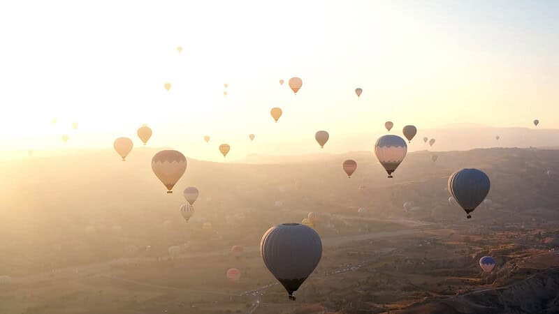 Mehrere Ballons über einer Grünlandfläche- Ballonfahrt- Ballons über Landschaft