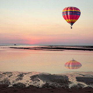 Ballonfahrt-Ostsee Bunter Heißluftballon über der Ostsee mit Strand und Sonnenuntergang am Himmel- Ballonfahrt-Ostsee