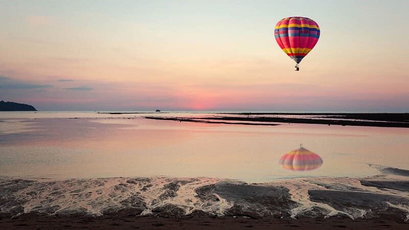 Bunter Heißluftballon über der Ostsee mit Strand und Sonnenuntergang am Himmel- Ballonfahrt-Ostsee