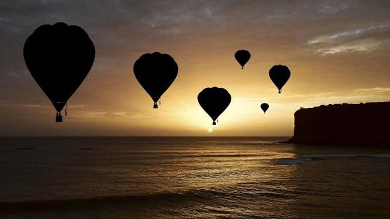 Mehrere Ballons über der Ostsee mit Inselrand bei Sonnenuntergang- Ballonfahrt- Sonnenuntergang