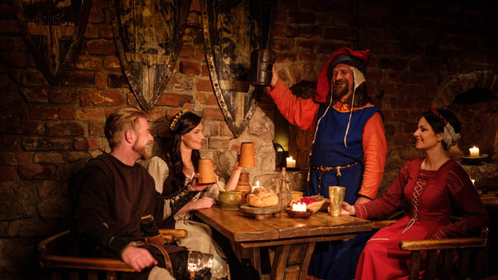 Vier Personen im mittelalterlichen Outfits Stoßen gemeinsam an - Ritteressen.