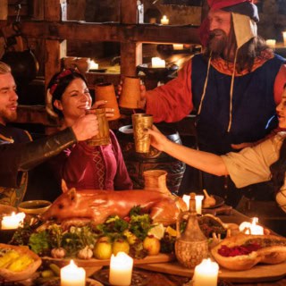 Vier Personen feiern gemeinsam beim Ritteressen im mittelalterlichem Ambiente.