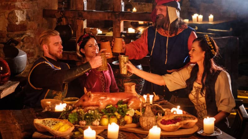 Vier Personen feiern gemeinsam beim Ritteressen im mittelalterlichem Ambiente.