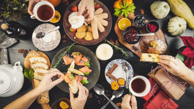 Gedeckter Tisch mit Kulinarischen Köstlichkeiten und Händen die sich Essen nehmen.