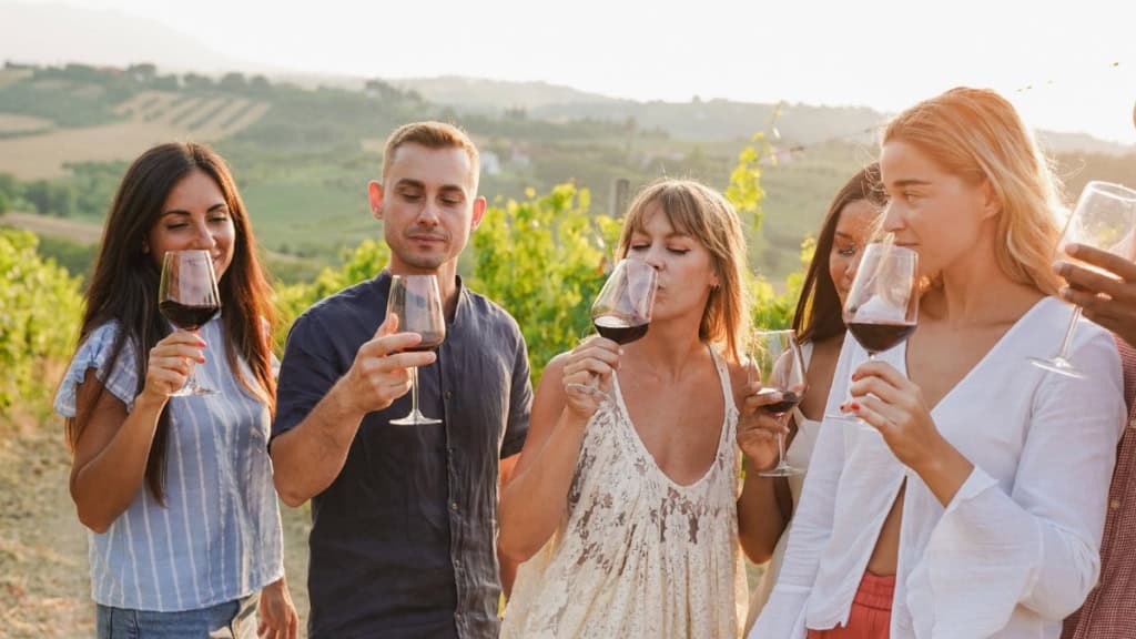 Weinwanderung - Gruppenverkostung Eine Gruppe von Menschen verkostet einen Rotwein während einer Weinwanderung.