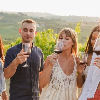 Eine Gruppe von Menschen verkostet einen Rotwein während einer Weinwanderung.