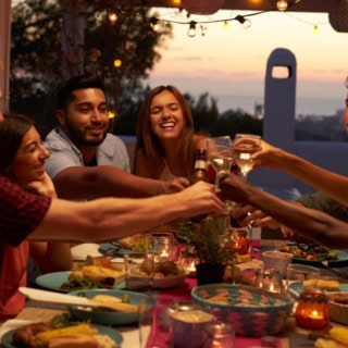 Freundesgruppe die an einem Gedecktem Tisch anstößt.