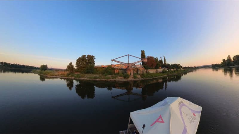 Floß fährt auf der Elbe an einem Kran vorbei.