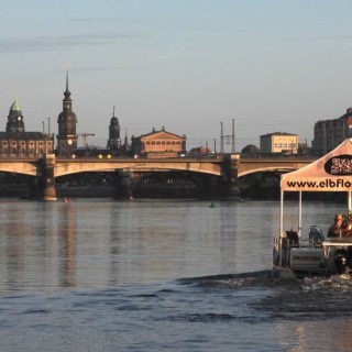 Floß fährt auf der Elbe an der Marienbrücke vorbei.